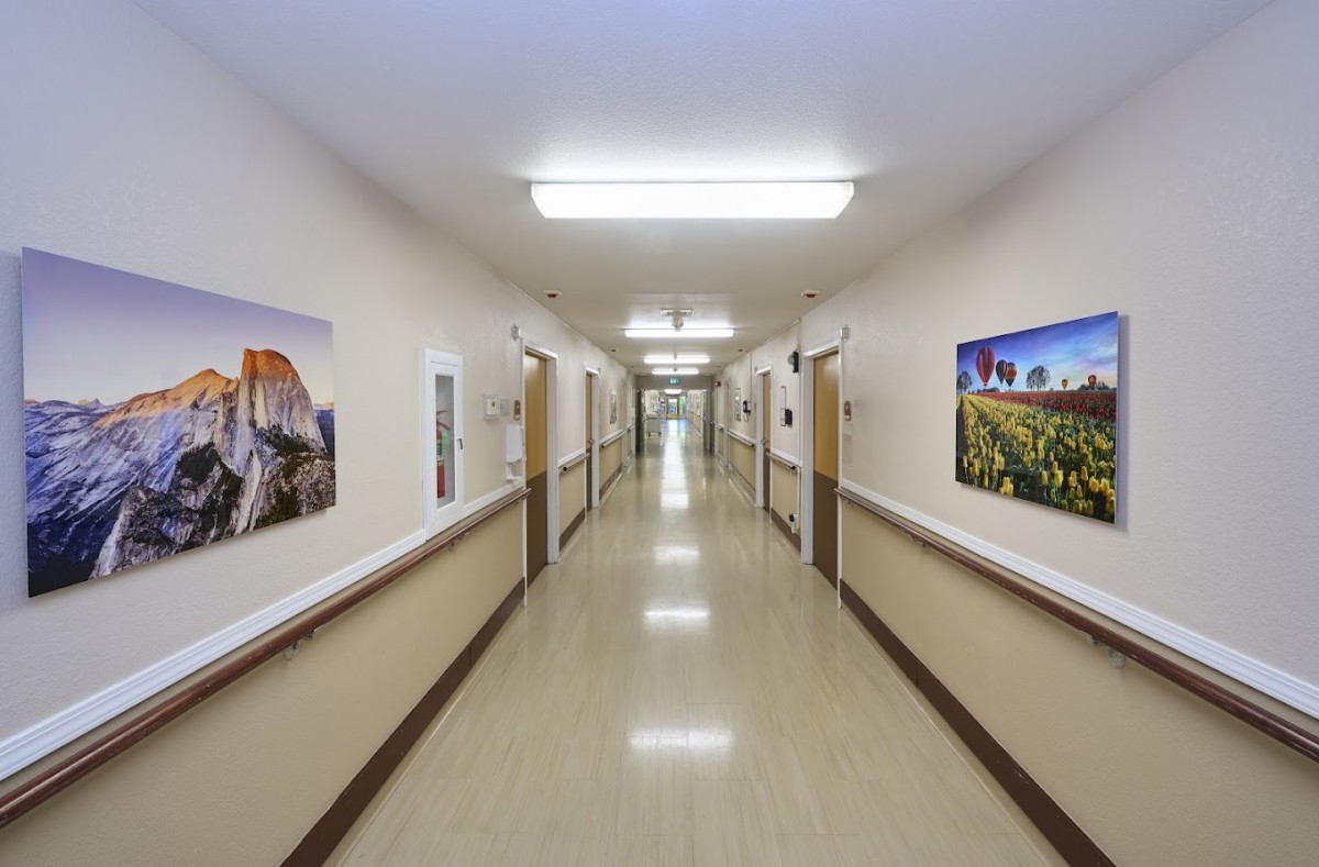 A clean hospital corridor with artwork on the walls and bright fluorescent lighting.