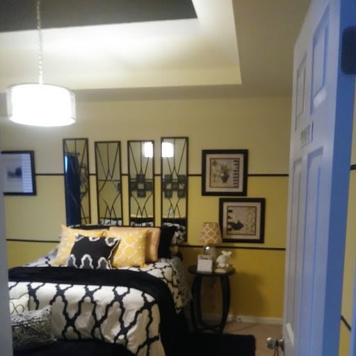 A modern bedroom with yellow walls, stylish artwork, and a cozy atmosphere.