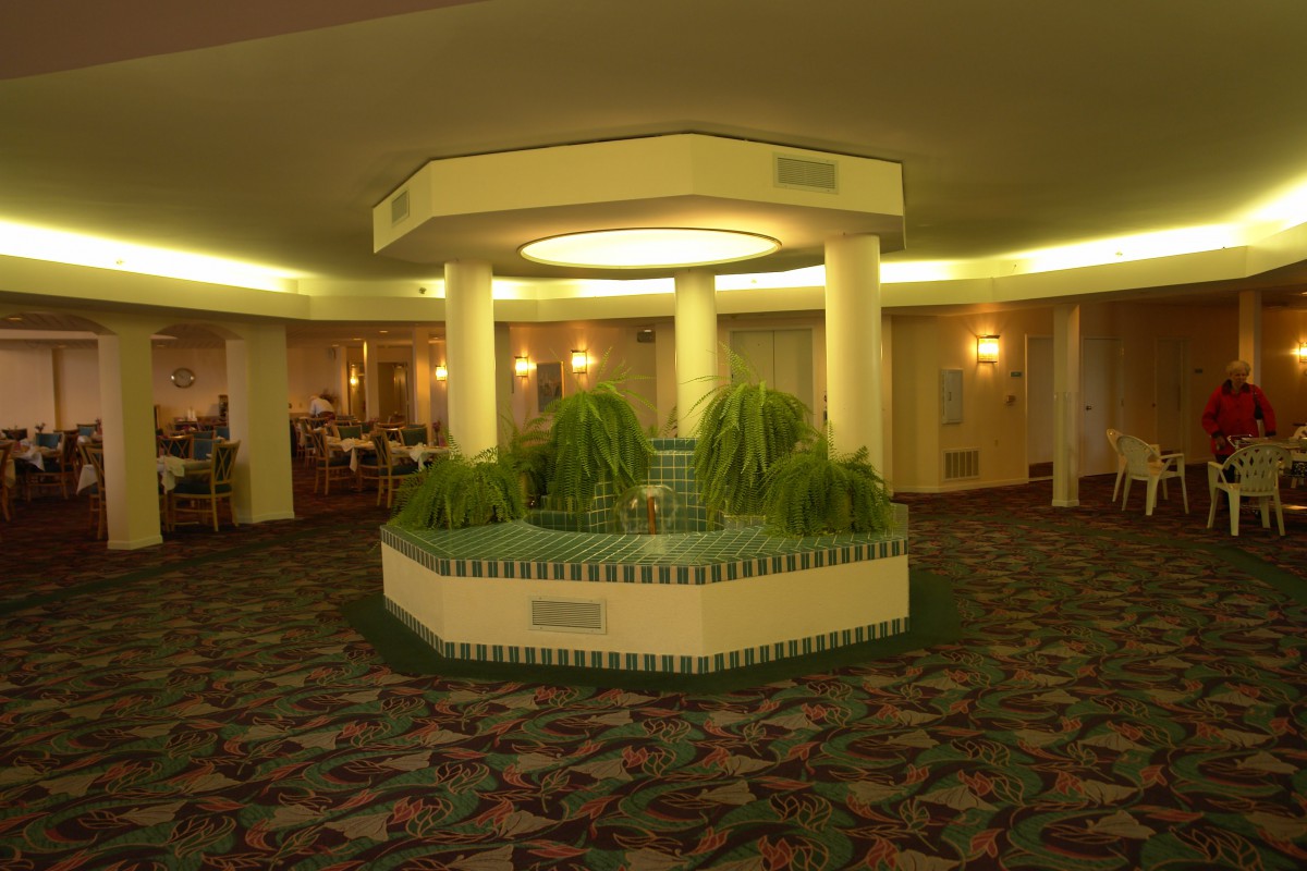 A hotel lobby with a central fountain surrounded by plants.