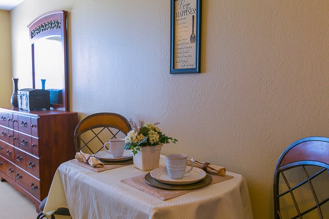 A cozy dining setup with two place settings and a floral centerpiece in a warmly lit room.