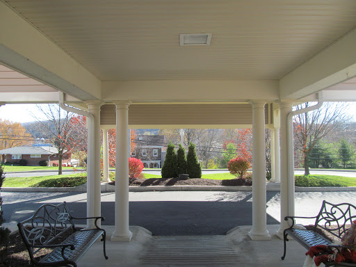 A serene entryway featuring decorative columns and benches, leading to a beautifully manicured garden.