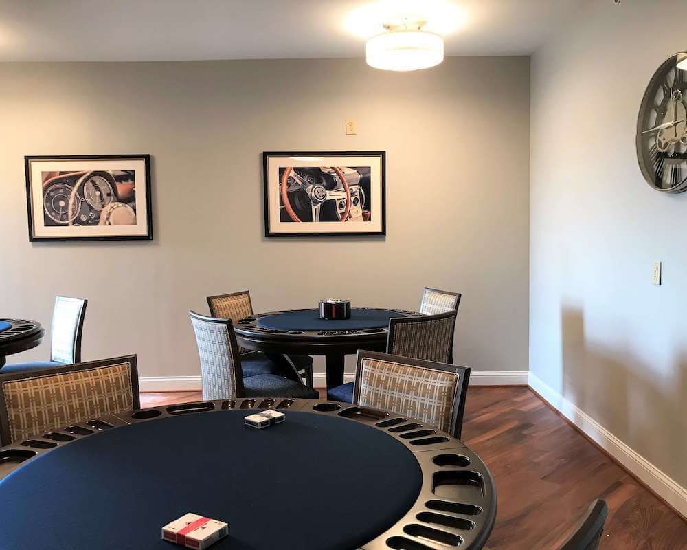 A modern poker room with round tables and stylish chairs, adorned with wall art.
