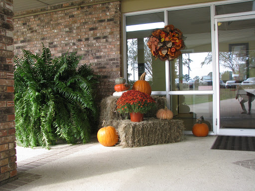 A vibrant autumn display featuring pumpkins, hay bales, and a decorative wreath, capturing the essence of fall.