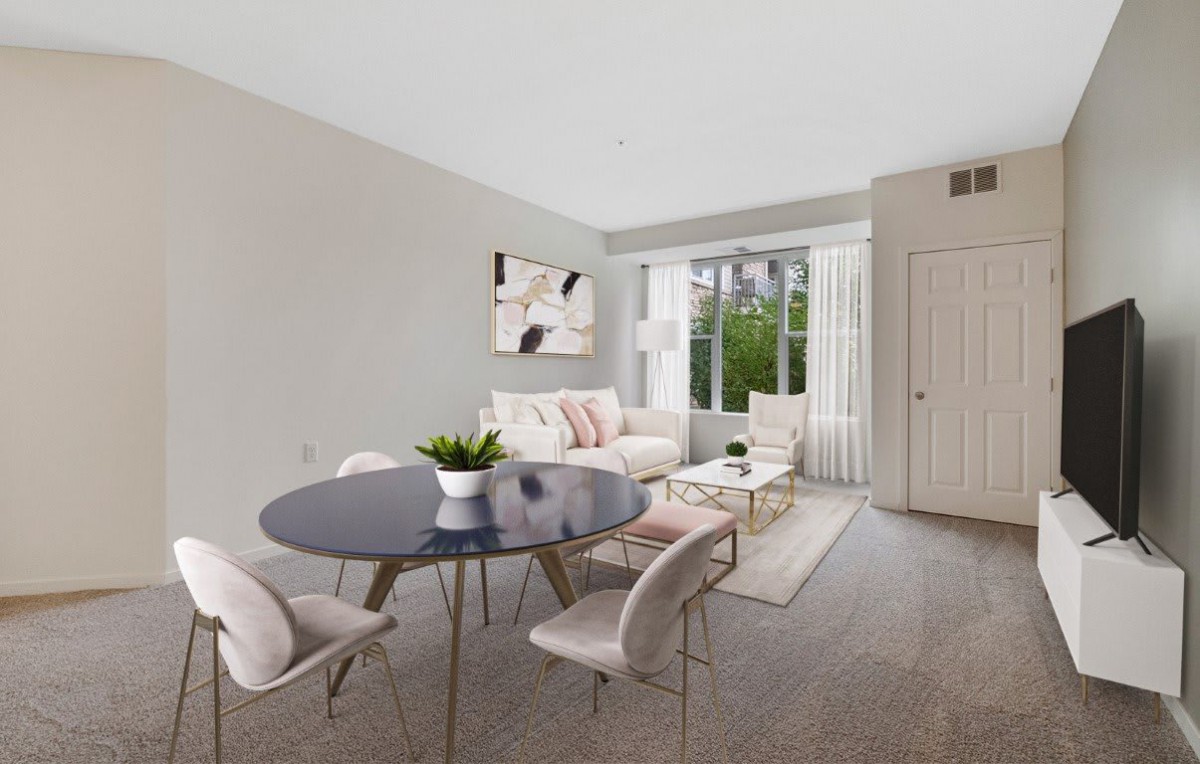 A modern living room with a dining area featuring neutral colors and minimalist design, enhanced by natural light and an indoor plant.