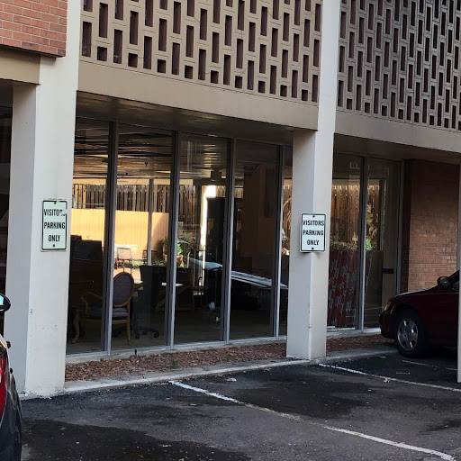 Entrance of a commercial building with large glass windows and a parking area.