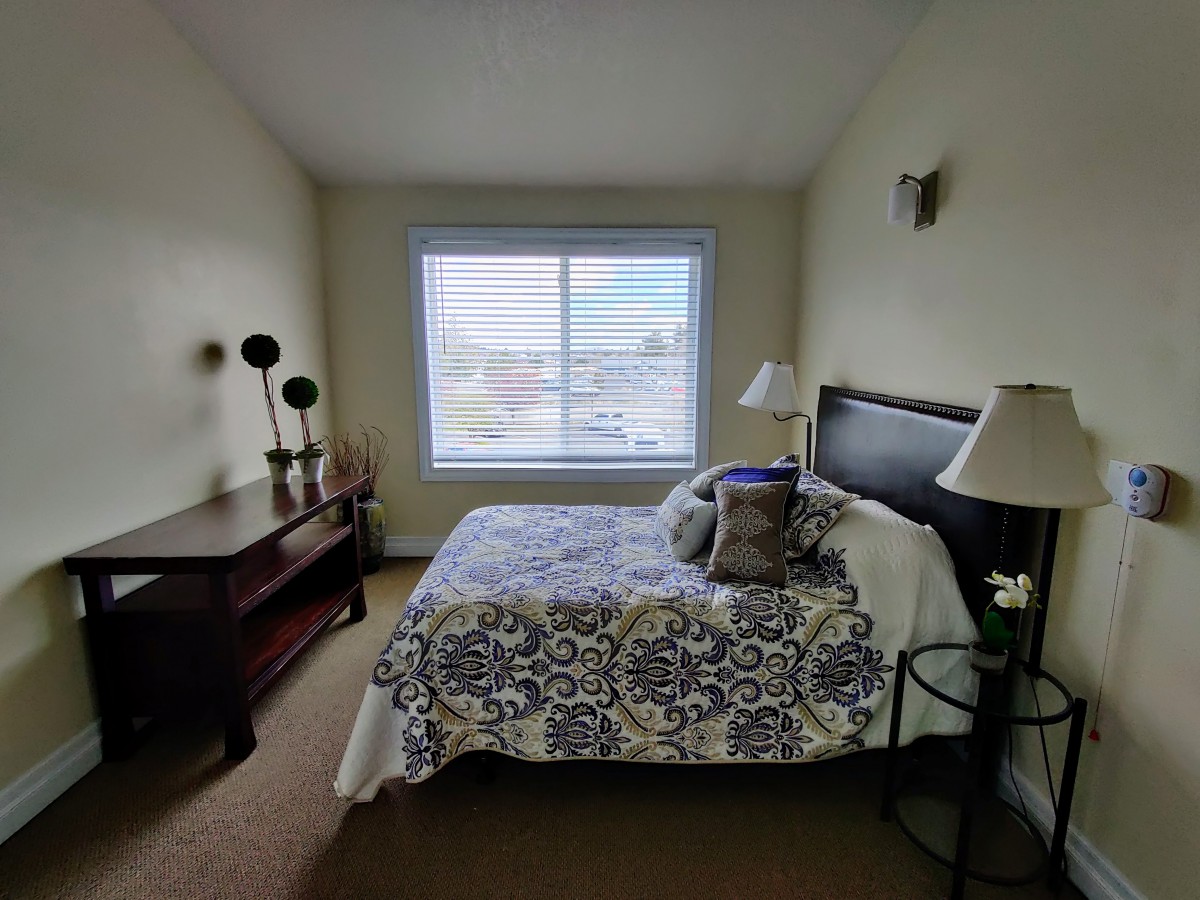 A cozy bedroom with a large window, decorated with patterned bedding and modern furnishings.