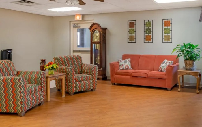 A cozy living room with a sofa, armchairs, and a grandfather clock.