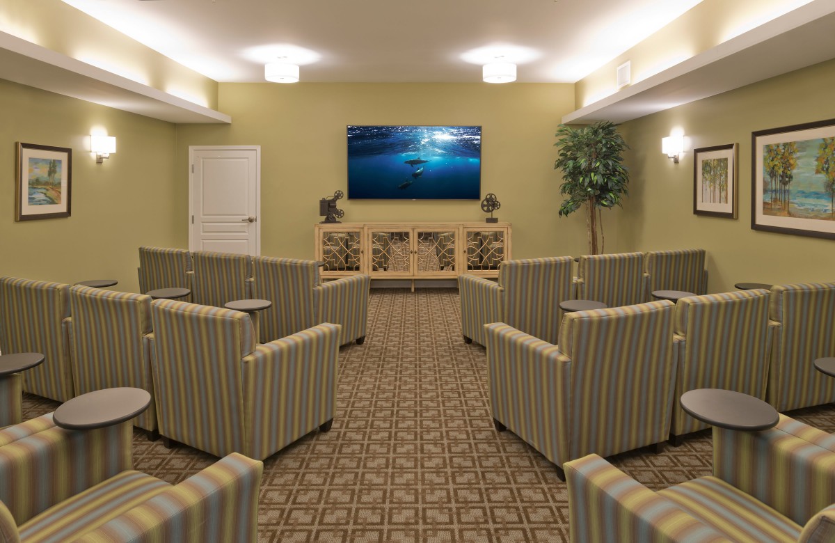 A cozy home theater room featuring striped seating and a large wall-mounted TV.