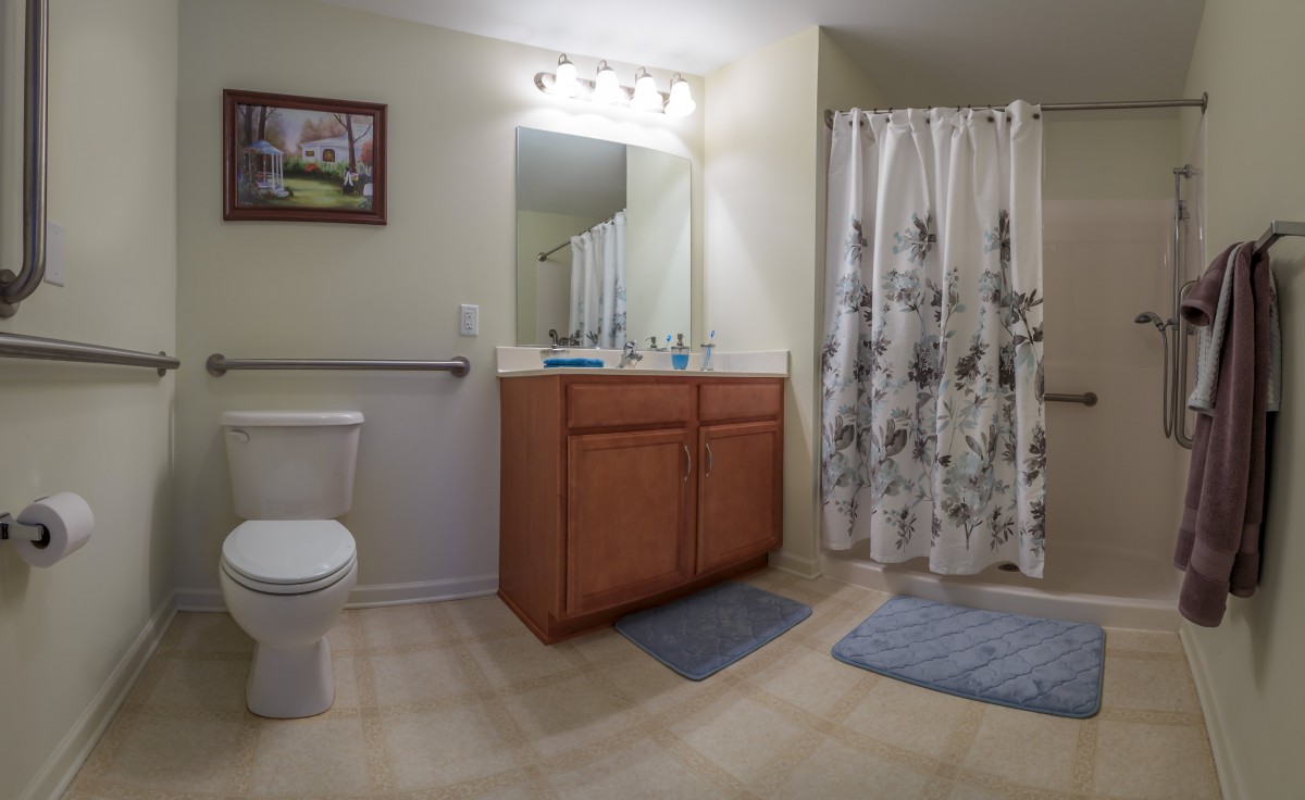 A clean and well-lit bathroom featuring a vanity with mirror, toilet, and shower area.