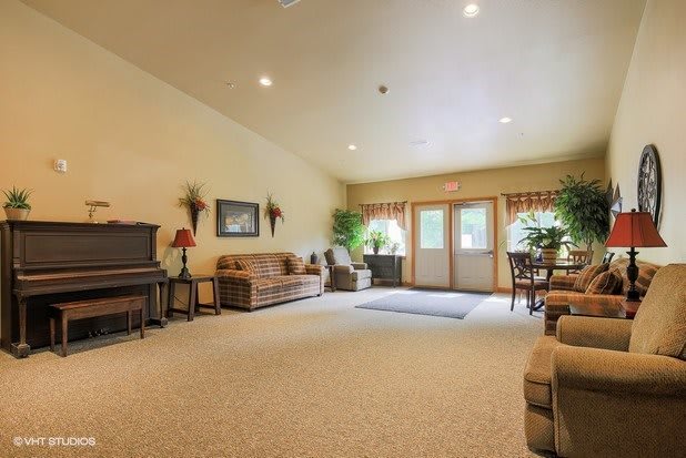 Spacious living room with sofas, a piano, and large windows letting in natural light.
