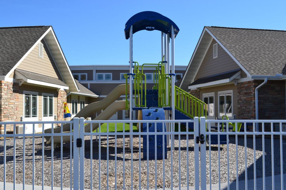 A fenced playground with a slide in a residential area.