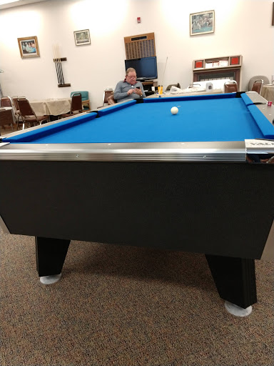 A pool table with a blue surface, set in a cozy game room.