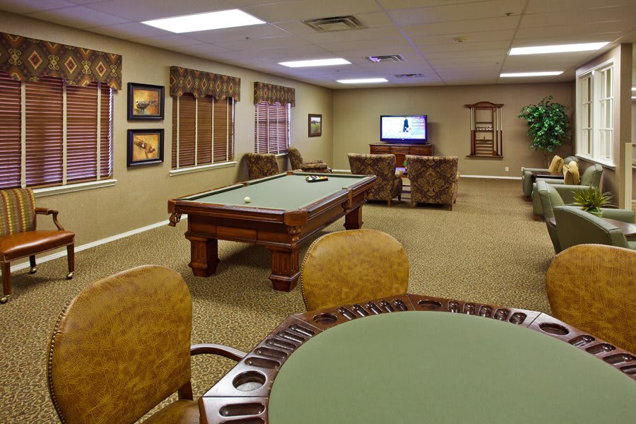 A cozy game room featuring a pool table and comfortable seating with a television.