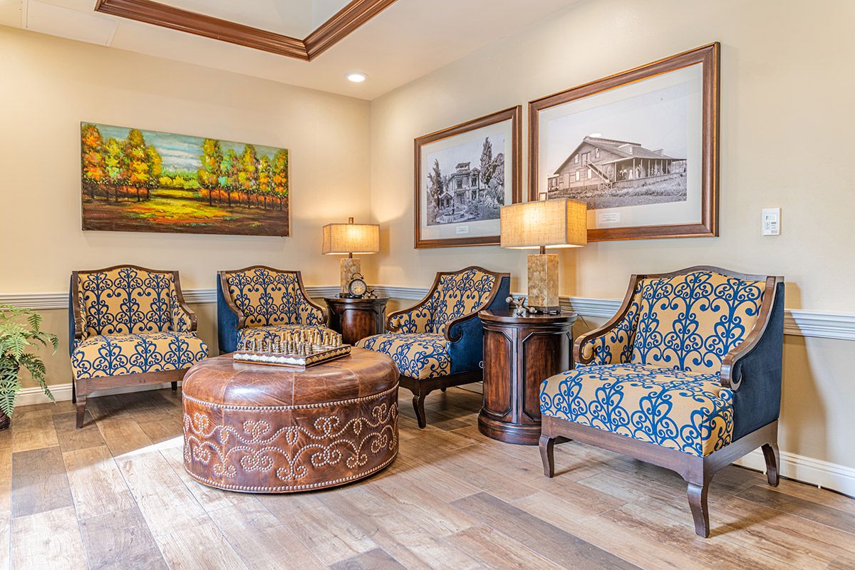 A cozy living room featuring elegant patterned chairs, ornate wooden table, and framed artwork on the walls.