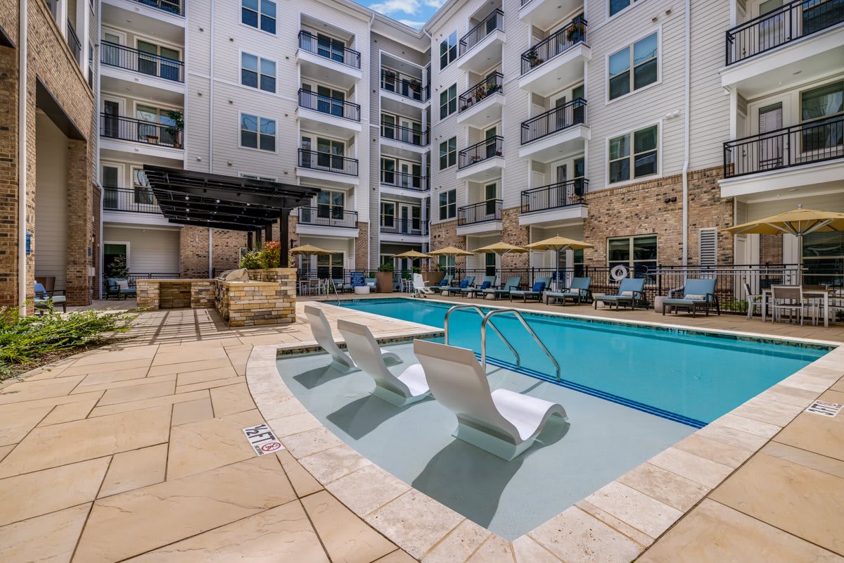 Modern apartment complex with an outdoor swimming pool and lounge area.