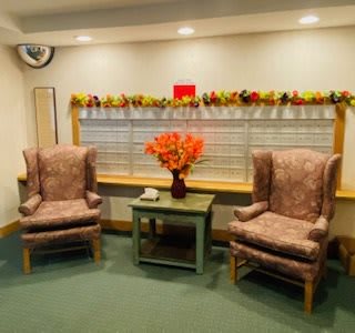 A cozy waiting area with two armchairs, a table adorned with a vibrant bouquet of flowers, and soft ambient lighting.