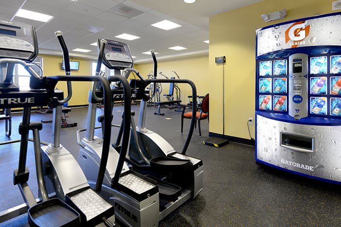 A modern gym with elliptical machines and a vending machine in the corner.