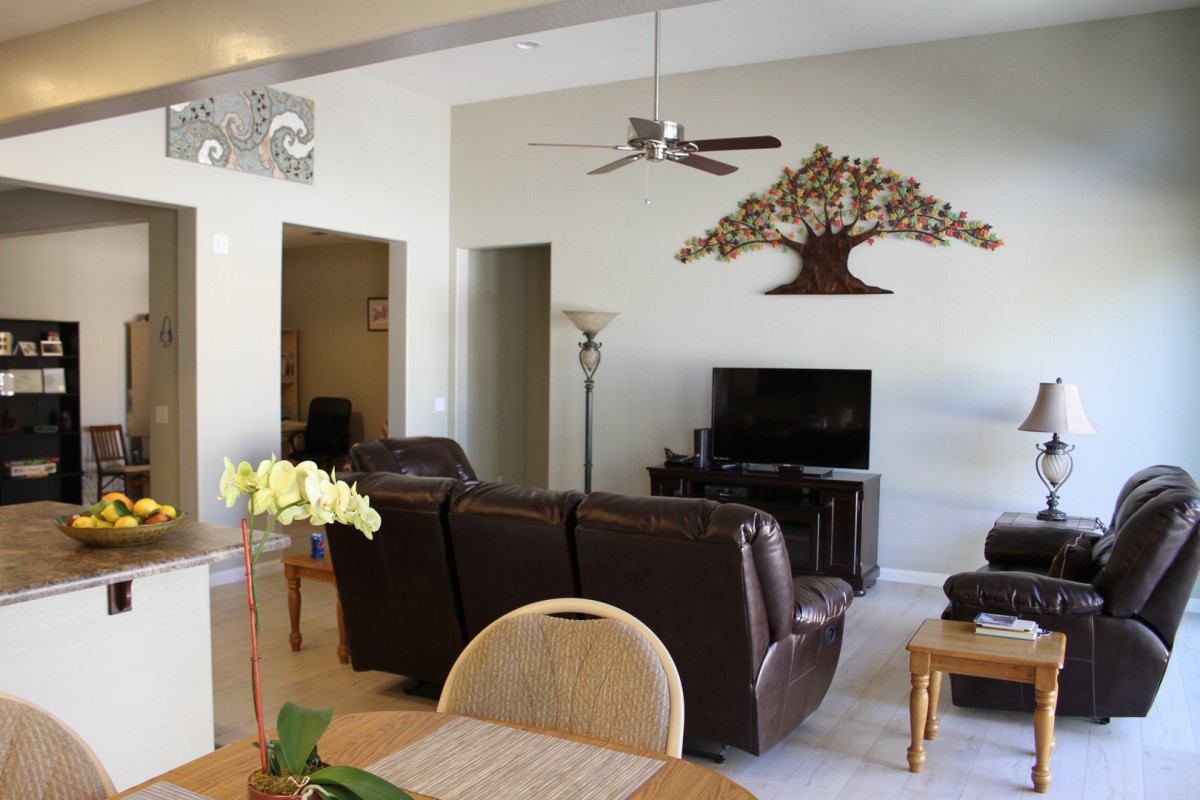A cozy living room with modern furniture, featuring a wall-mounted TV and decorative wall art.