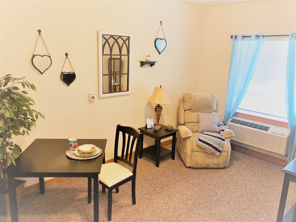 A cozy living space featuring a recliner, a small dining table with two chairs, and decorative wall art.