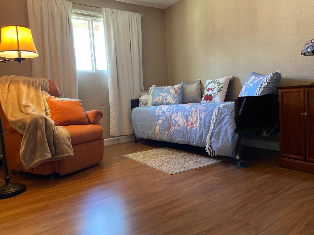 A cozy living room with a sofa, armchair, and window with curtains.