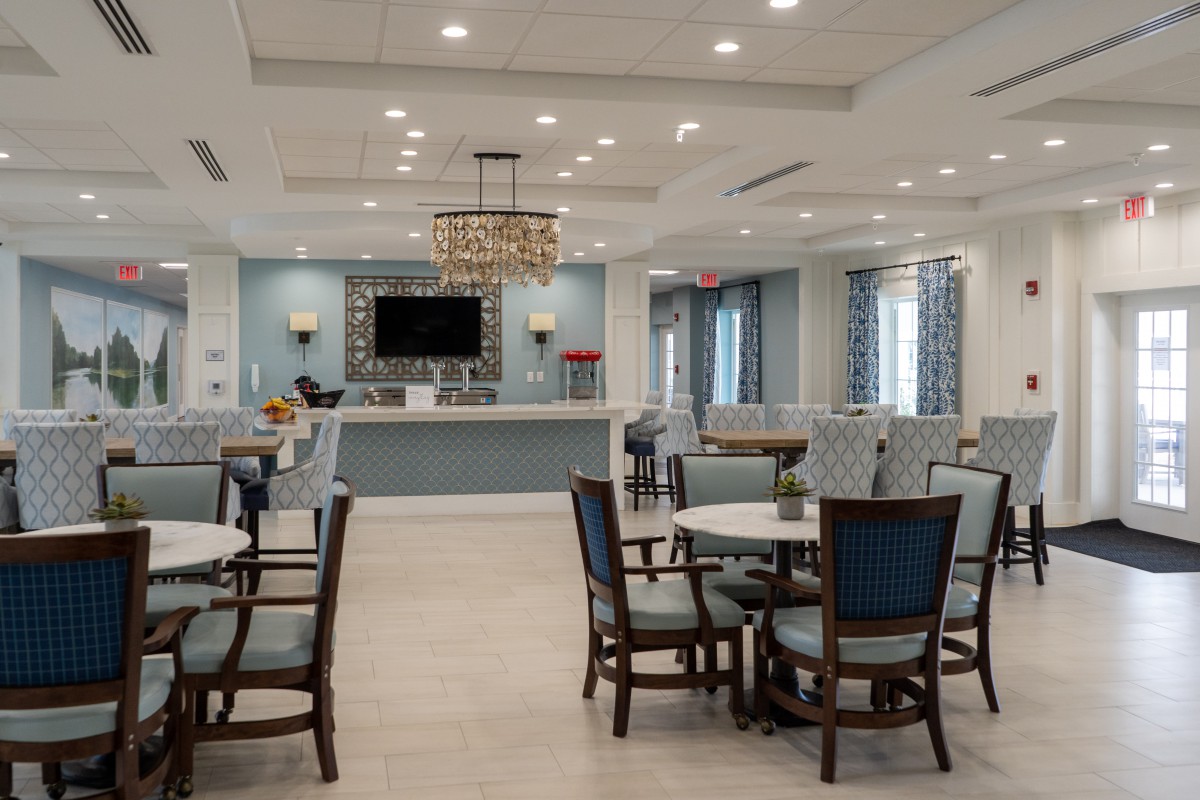 A modern and spacious dining area with elegant chandeliers and multiple tables arranged for seating.