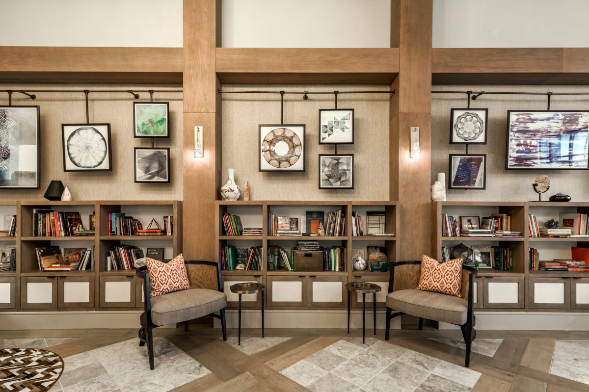 A cozy library nook with bookshelves, chairs, and decorative artwork.