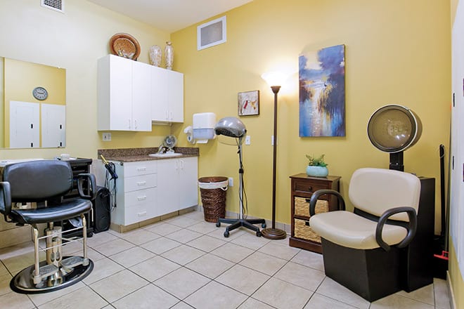 A cozy hair salon room with styling equipment and comfortable seating.