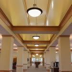 A spacious hallway with columns and modern ceiling lights, featuring wooden accents.