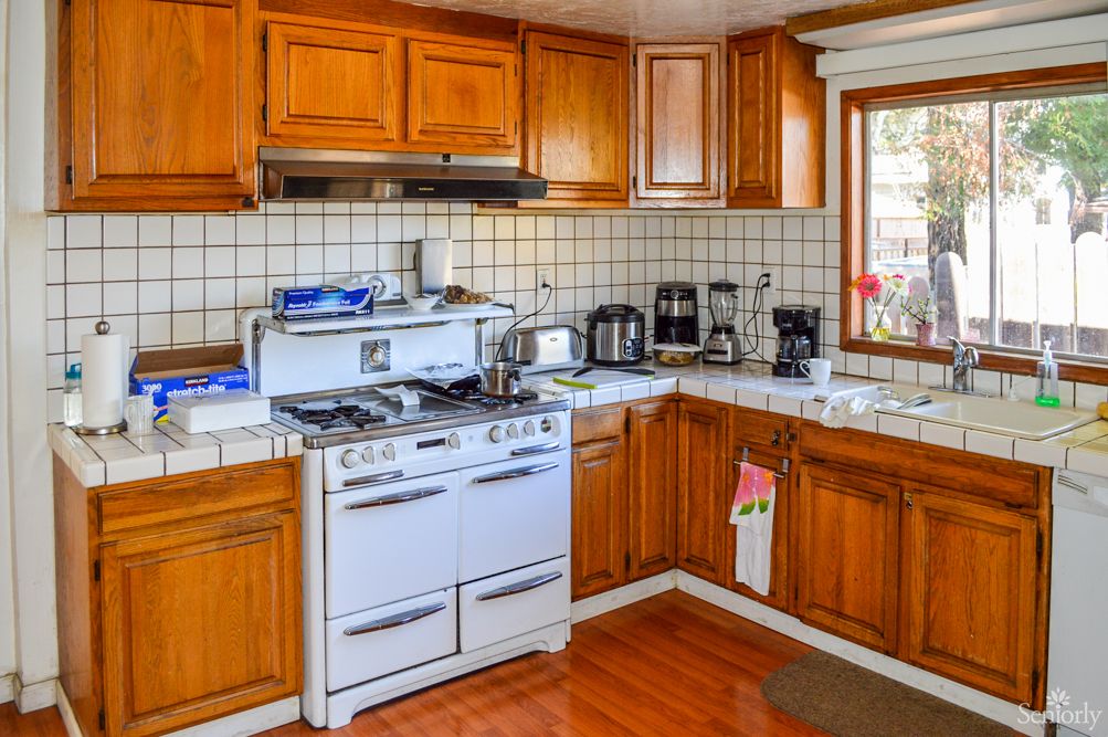 A cozy kitchen with wooden cabinets and a retro stove, filled with various appliances.