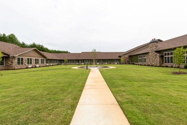 A view of a building with a courtyard, featuring a grassy lawn and a central pathway.
