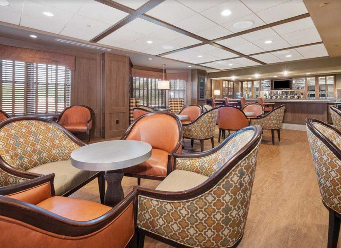A cozy lounge area with comfortable seating and a bar in the background.