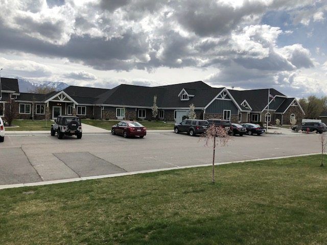 A suburban building with a parking lot and several cars under a cloudy sky.