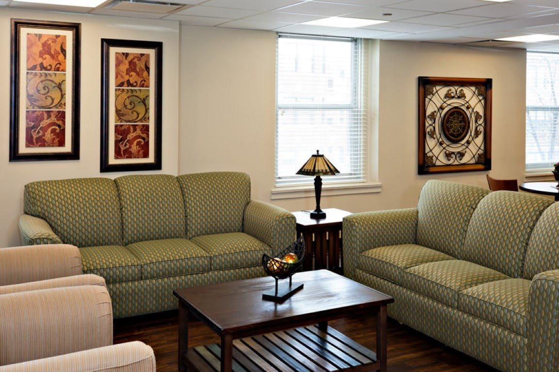 A cozy living room with green sofas, a wooden coffee table, and decorative artwork on the walls.