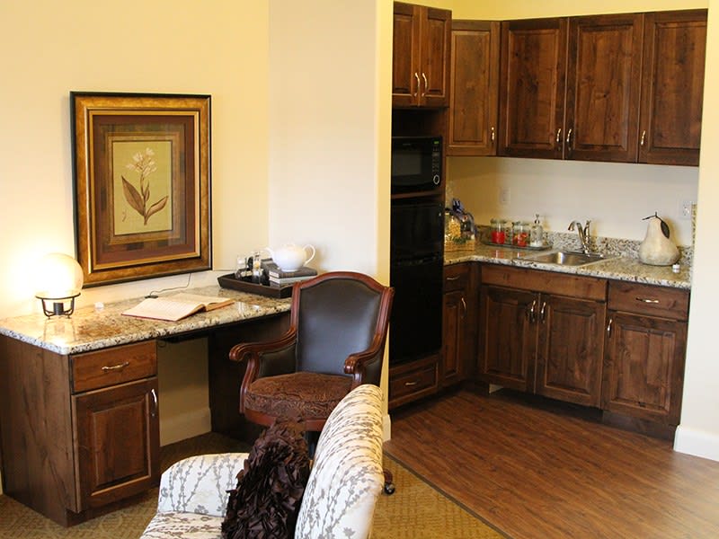 A cozy kitchen area with wooden cabinets and a small desk workspace.