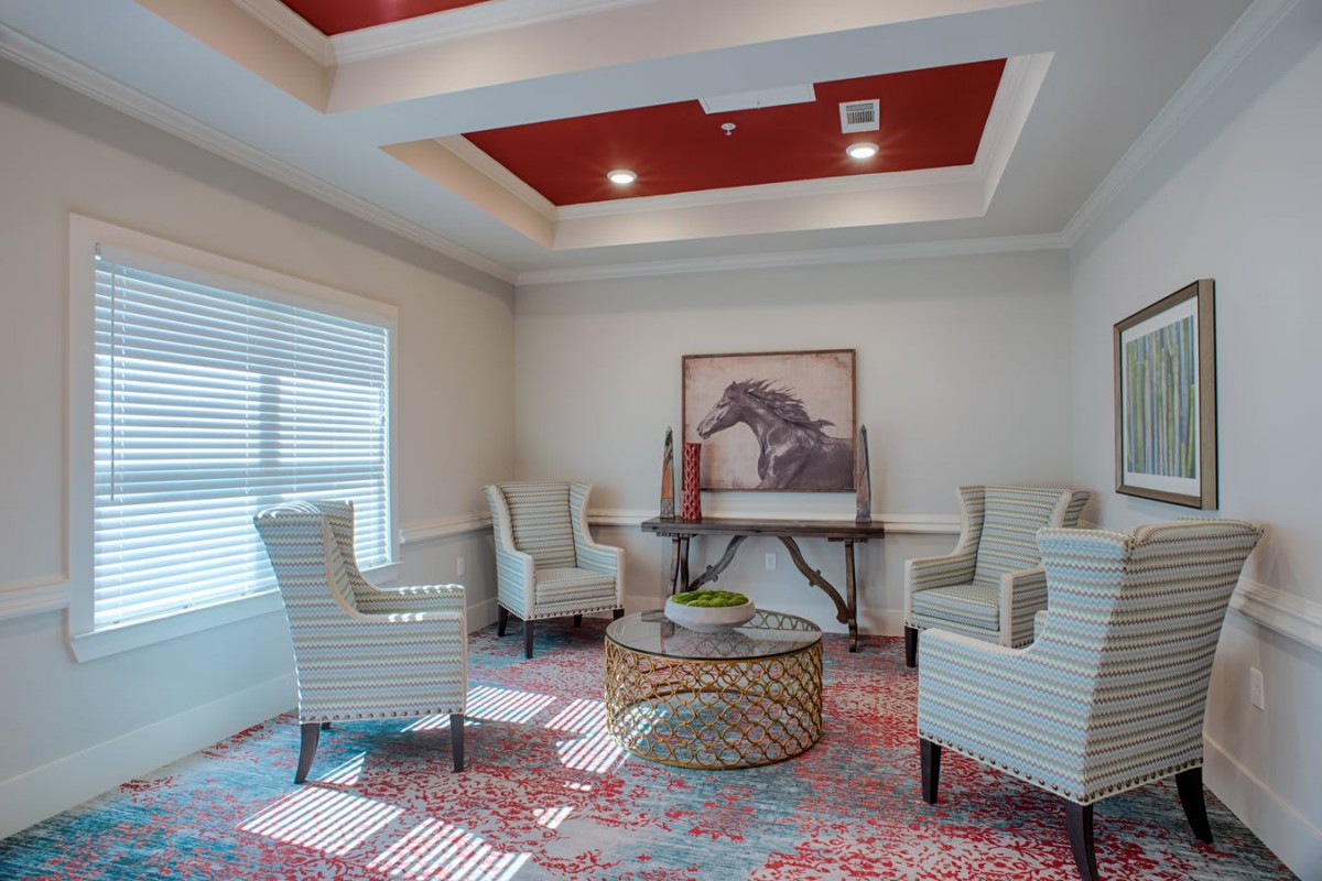 A cozy living room with elegant armchairs, a round table, and decorative artwork under a stylish ceiling.