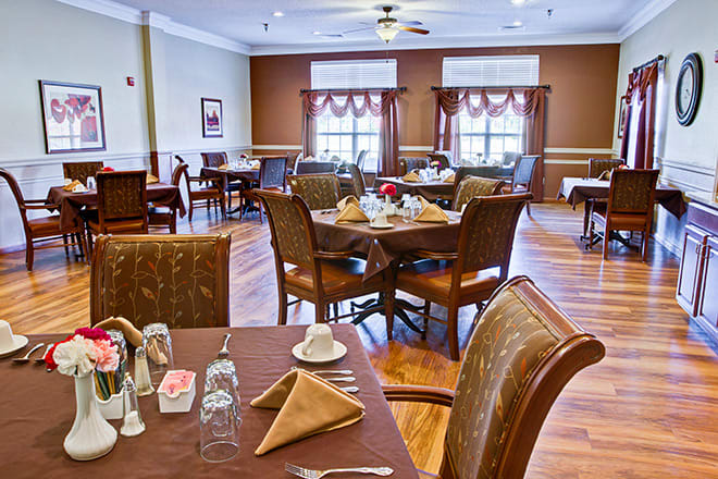 A neatly arranged dining room with well-set tables and chairs, ready for guests.