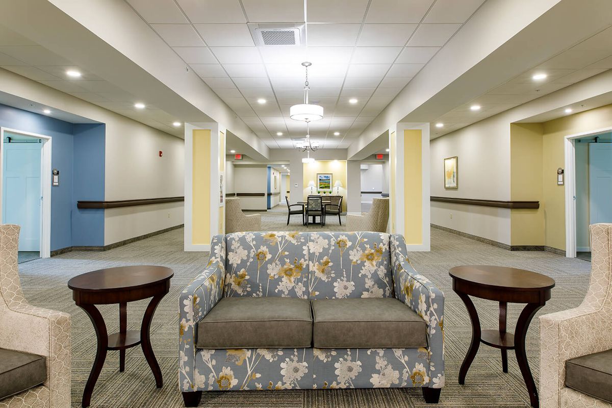 A well-lit lobby area with a floral-patterned sofa and matching side tables.