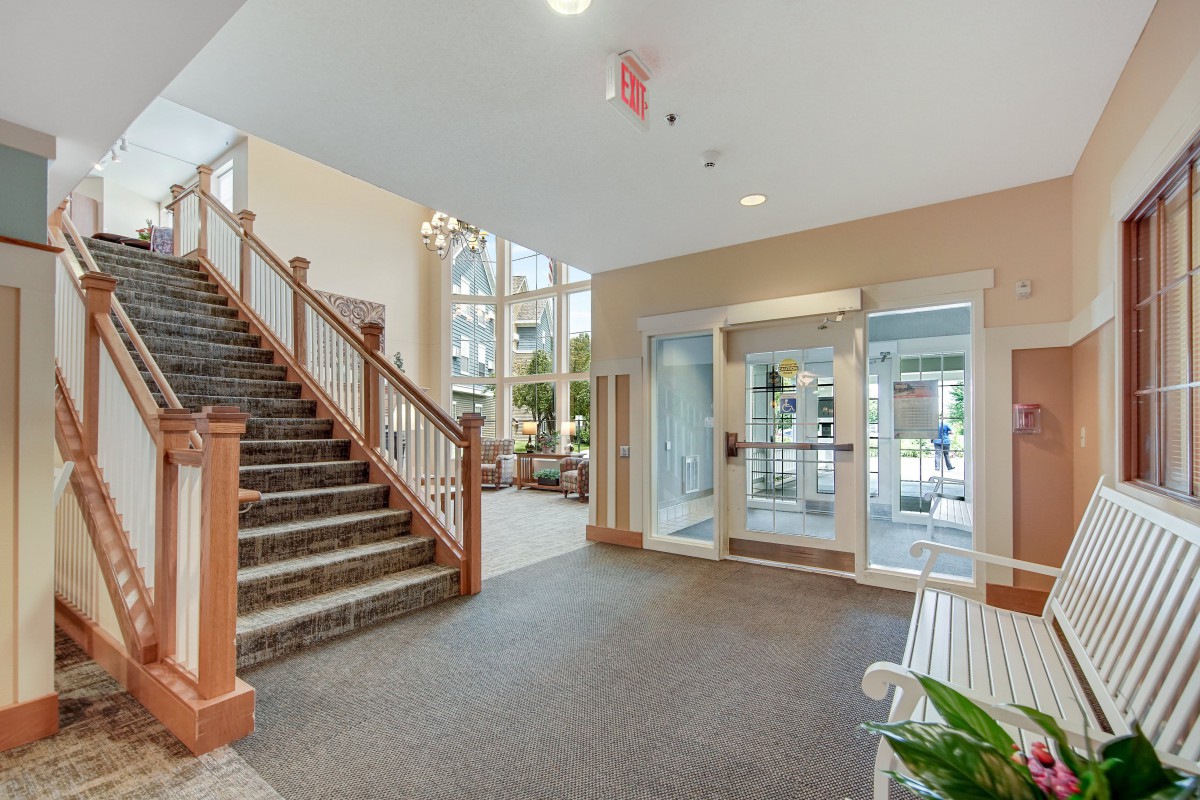 A bright and welcoming lobby area featuring a staircase and glass doors.