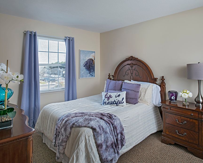 A cozy bedroom with a bed adorned with purple accents and matching curtains.