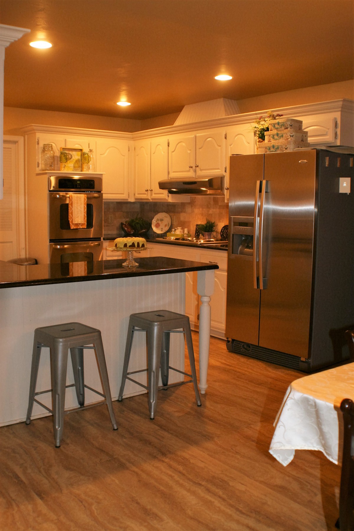 A modern kitchen with stainless steel appliances and counter stools.