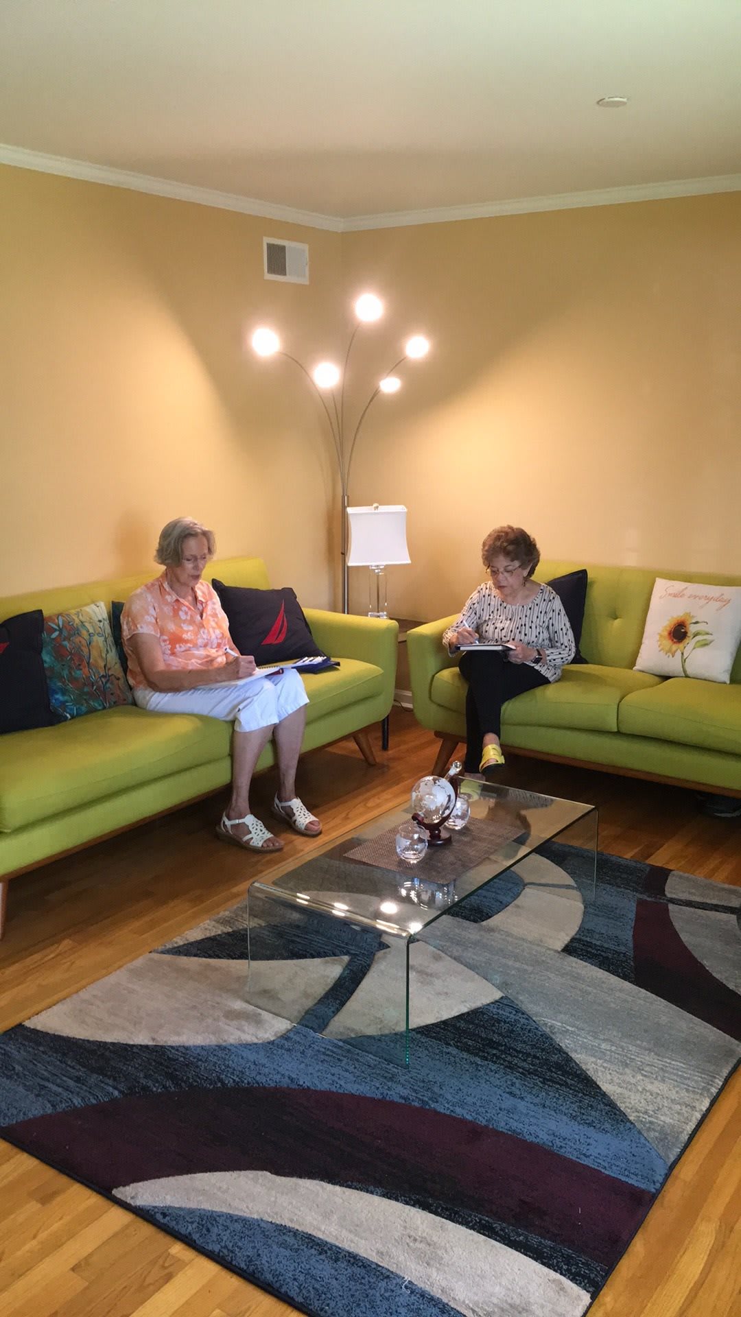 Two people sitting on a green sofa in a cozy living room reading.