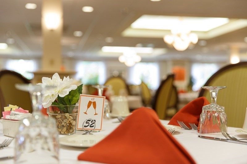 Elegant table setting for a wedding with floral centerpiece and orange napkins.