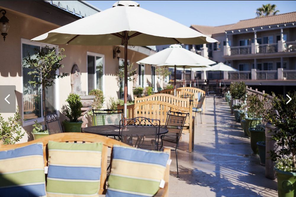 An inviting outdoor patio with wooden benches, tables, and umbrellas for shade.