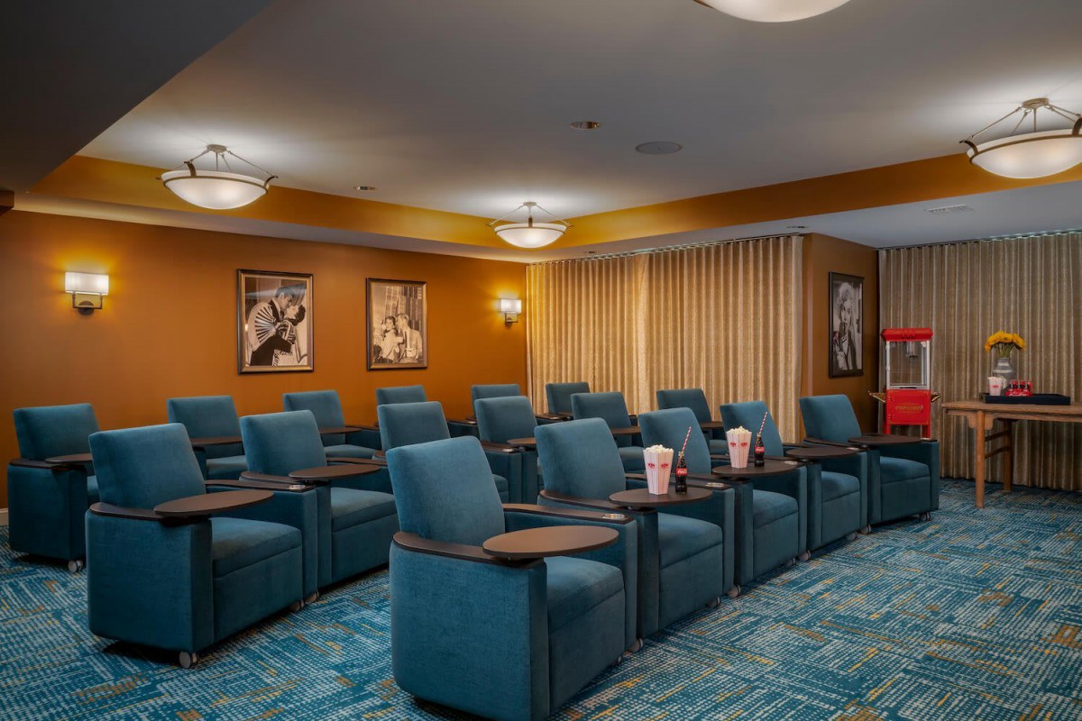 A cozy home theater room with multiple rows of blue reclining chairs, adorned with movie posters on the walls.