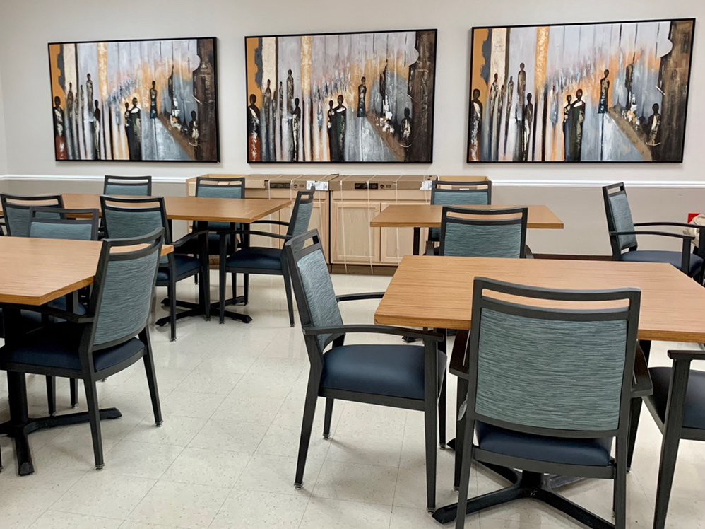 A modern dining area featuring several tables and chairs with abstract artwork on the walls.