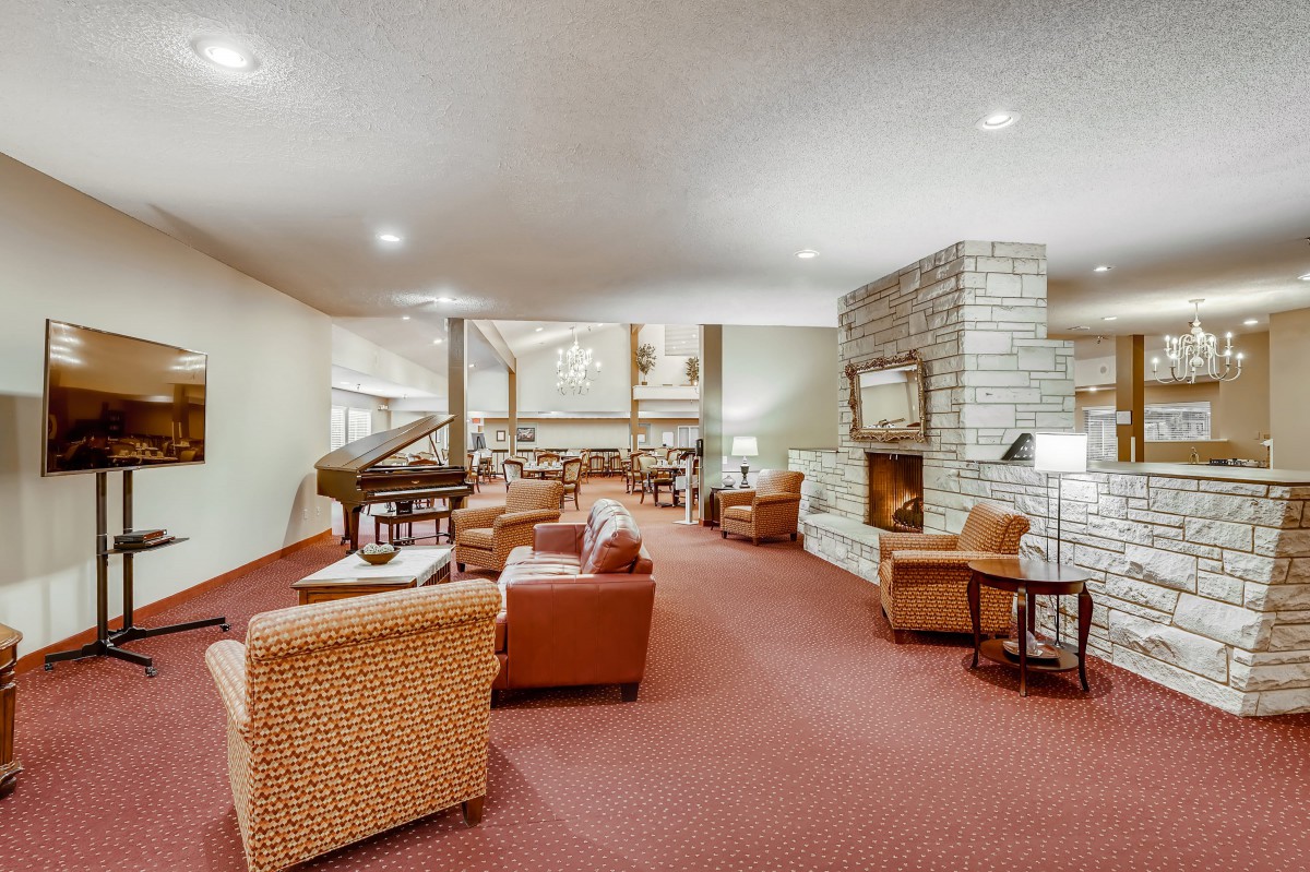 A spacious lounge area with comfortable seating, a fireplace, and a grand piano.