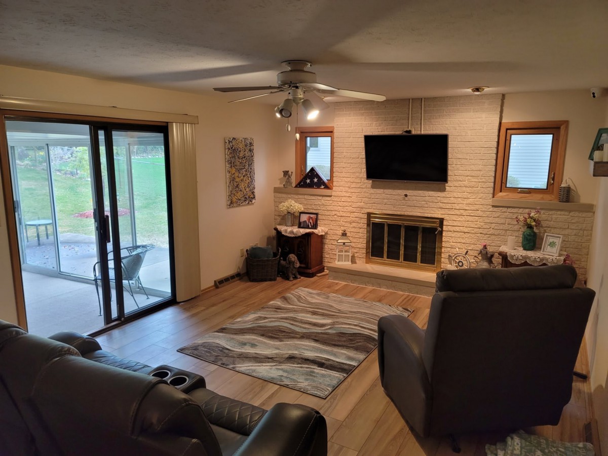 A cozy living room with a sofa, fireplace, TV, and sliding glass doors leading to an outdoor area.