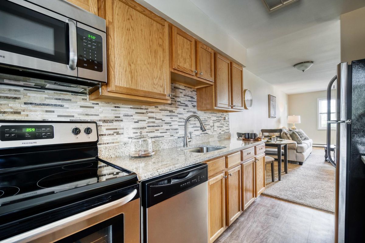 A modern kitchen featuring wood cabinets, stainless steel appliances, and a stylish backsplash.