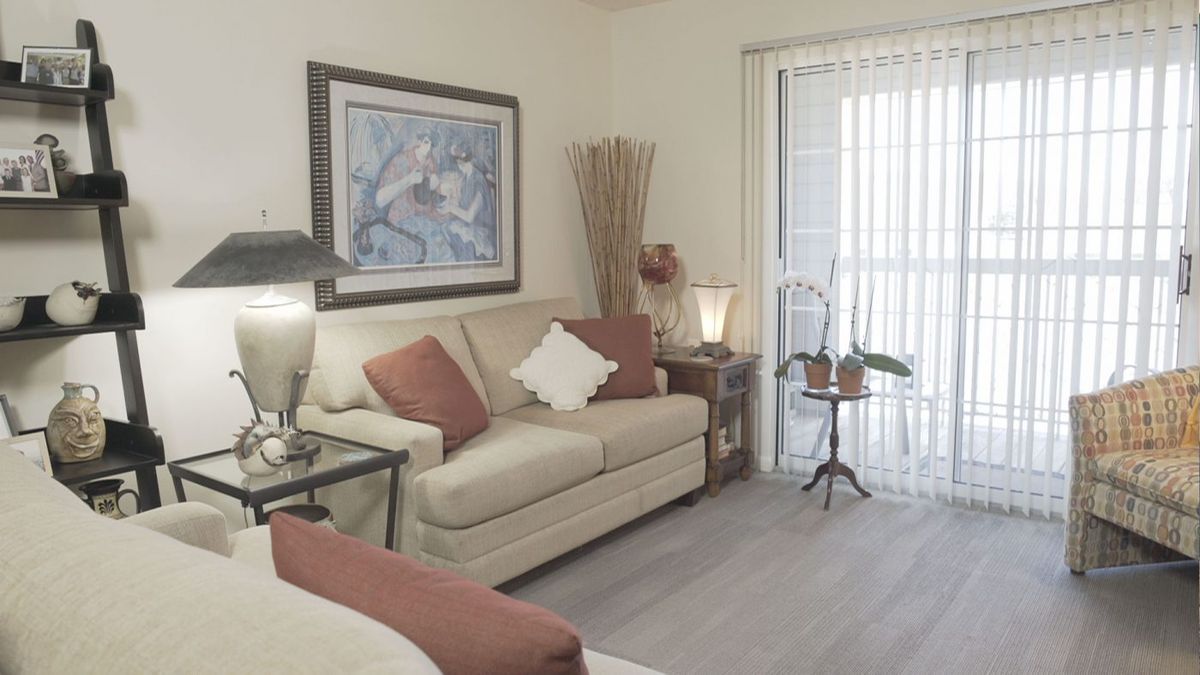 A cozy living room with soft tones, featuring a comfortable sofa, framed artwork, and decorative accents.