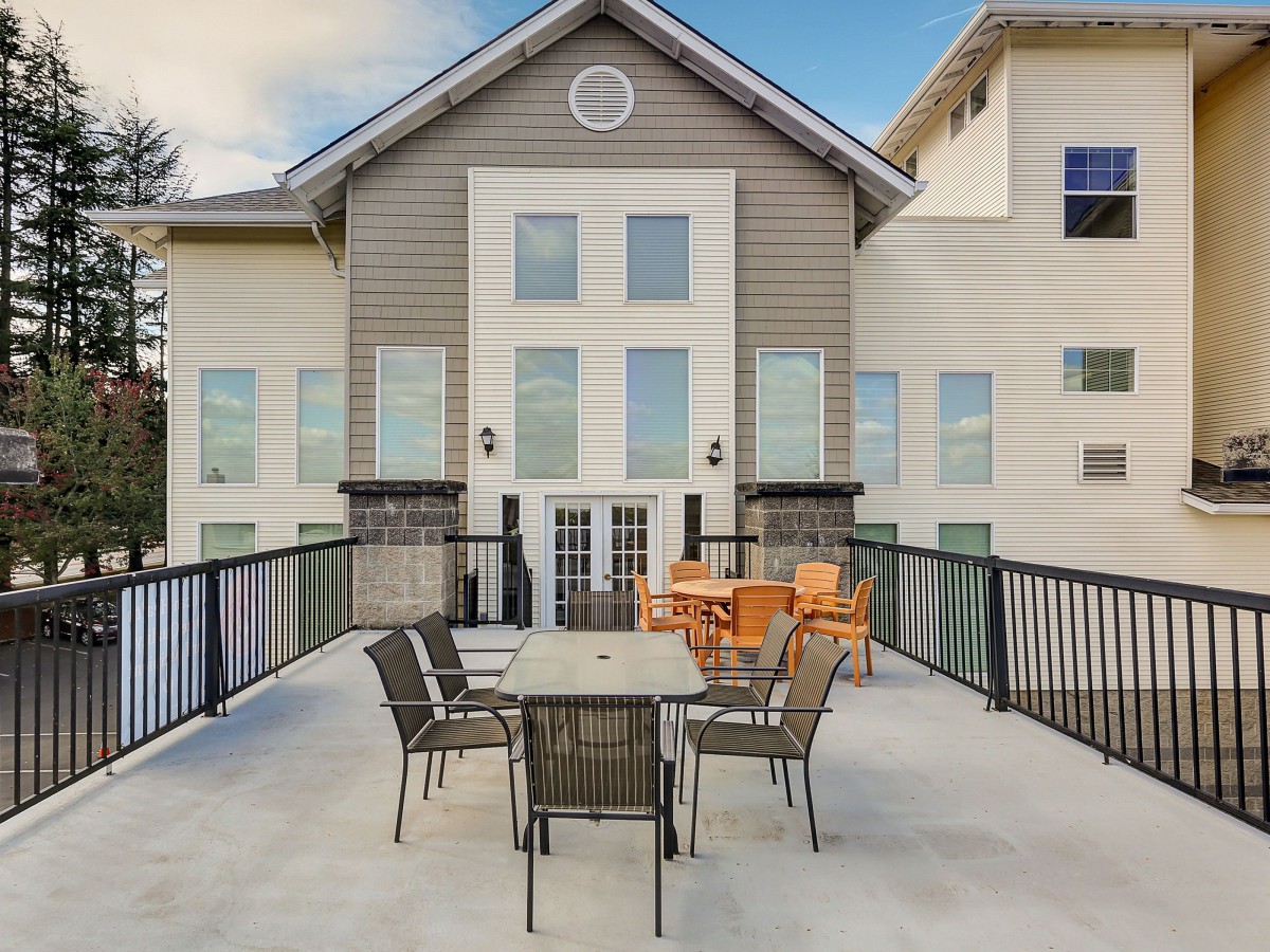 A modern building with a spacious patio featuring tables and chairs.